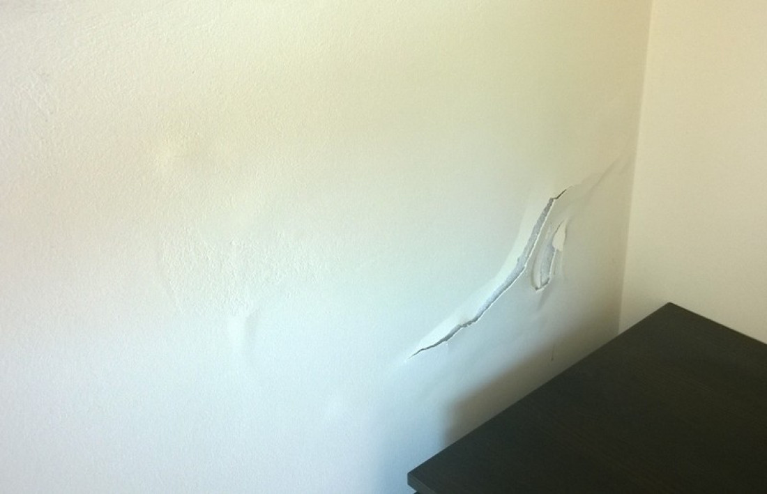 Co może być przyczyną uszkodzenia tynku na ścianie sypialni sąsiadującej z łazienką?